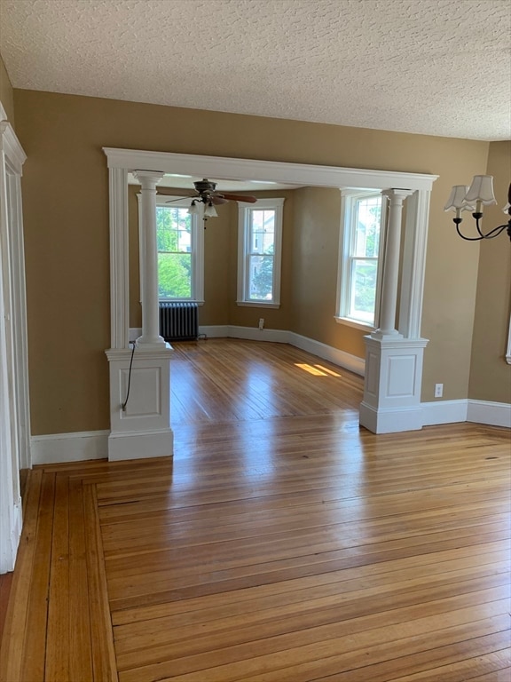 unfurnished living room featuring plenty of natural light, radiator heating unit, and a textured ceiling