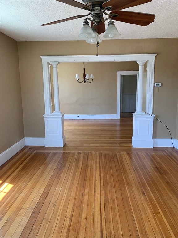 empty room with ceiling fan with notable chandelier, hardwood / wood-style floors, and a textured ceiling