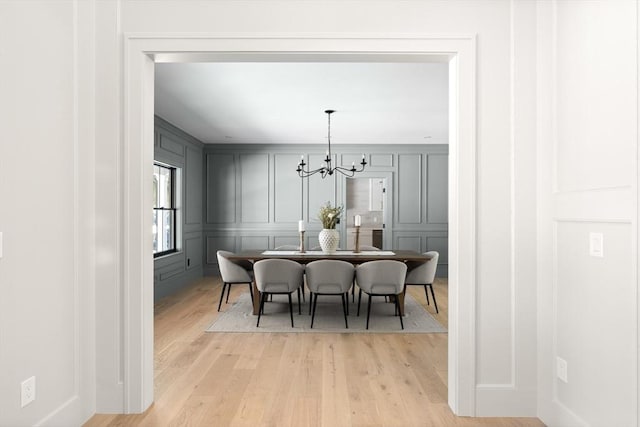 dining area with light hardwood / wood-style flooring and a notable chandelier