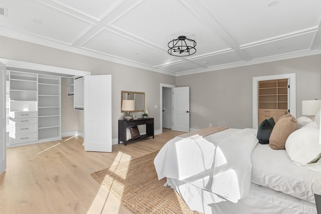 bedroom with light wood-type flooring, a closet, a spacious closet, and coffered ceiling