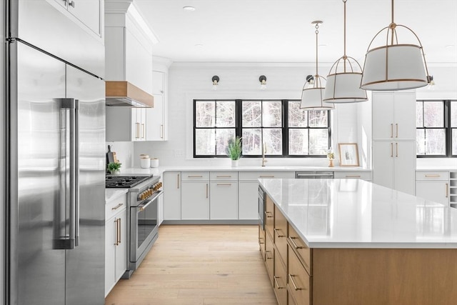 kitchen featuring custom exhaust hood, hanging light fixtures, light wood-type flooring, premium appliances, and white cabinets