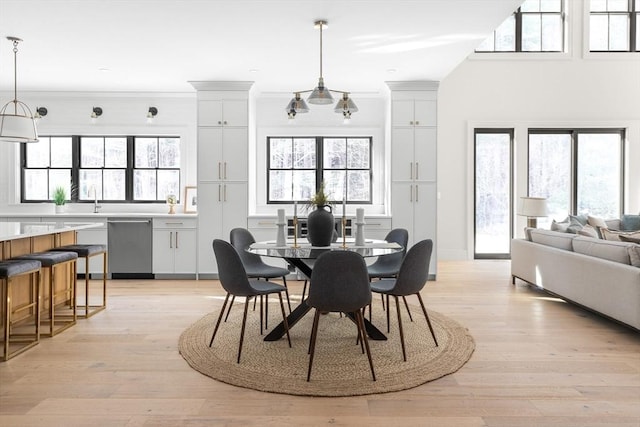 dining area with sink, a wealth of natural light, crown molding, and light wood-type flooring