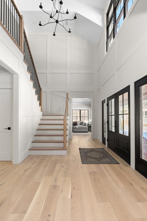 entryway featuring french doors, a notable chandelier, a high ceiling, and light hardwood / wood-style flooring