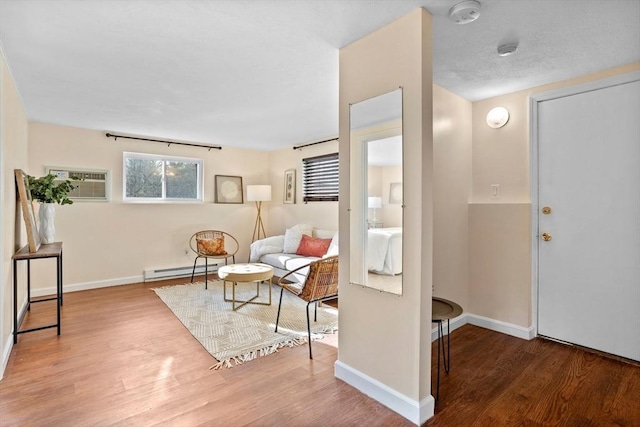 foyer entrance featuring a wall unit AC, hardwood / wood-style floors, and a baseboard radiator