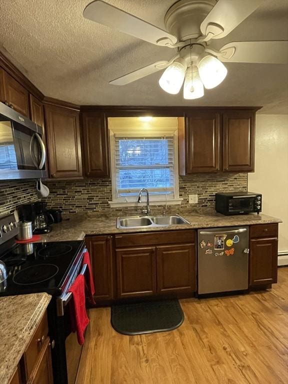 kitchen featuring sink, light wood-type flooring, ceiling fan, stainless steel appliances, and backsplash