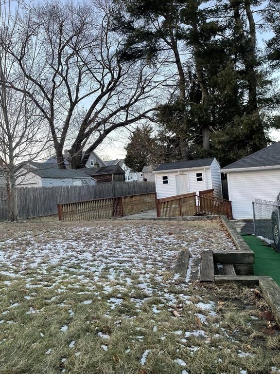 snowy yard featuring a wooden deck and a shed