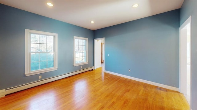 spare room featuring baseboard heating, recessed lighting, wood finished floors, and baseboards