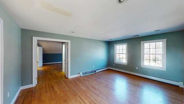 unfurnished room with a baseboard heating unit, baseboard heating, baseboards, and wood finished floors