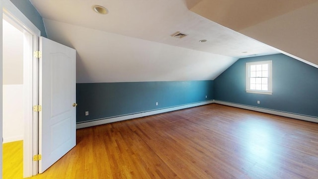 additional living space featuring lofted ceiling, wood finished floors, visible vents, baseboards, and baseboard heating