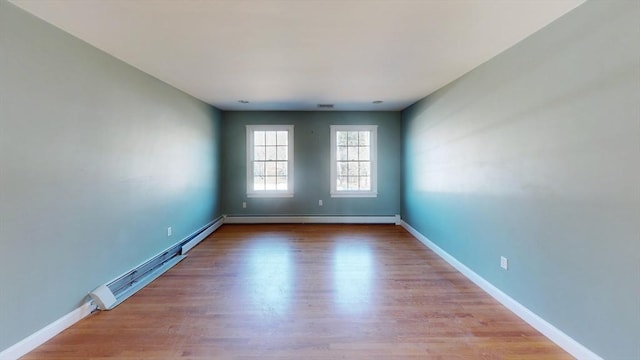 spare room featuring baseboard heating, wood finished floors, and baseboards