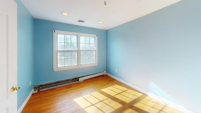 spare room with baseboards, a baseboard radiator, visible vents, and wood finished floors