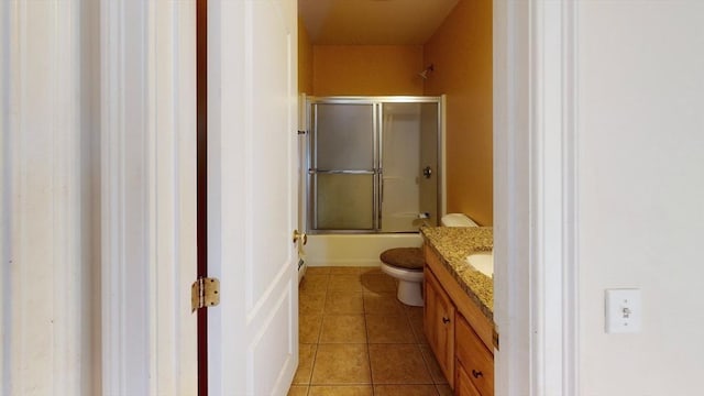 bathroom featuring toilet, vanity, combined bath / shower with glass door, and tile patterned floors