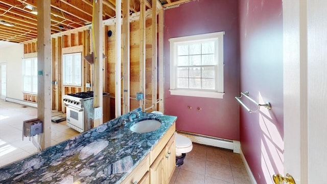 bathroom featuring a wealth of natural light, tile patterned flooring, toilet, and baseboard heating