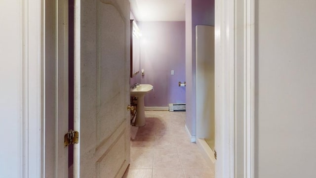 hallway featuring baseboards, baseboard heating, and light tile patterned floors