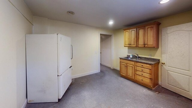 kitchen featuring recessed lighting, a sink, baseboards, freestanding refrigerator, and dark countertops