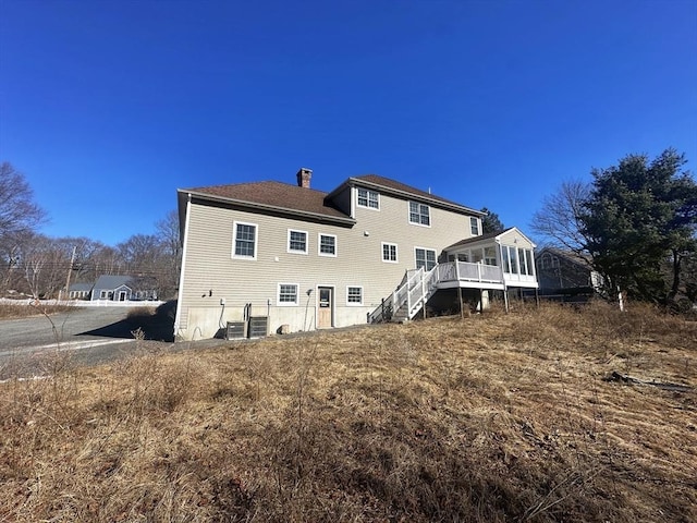 back of property with a chimney and stairway