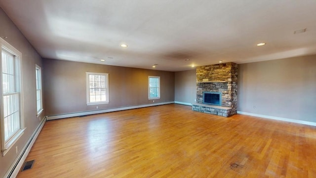 unfurnished living room featuring a baseboard heating unit, a fireplace, baseboards, baseboard heating, and light wood finished floors