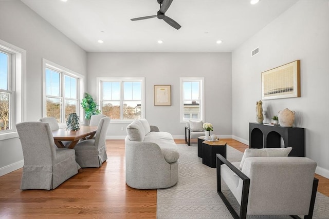 living room with recessed lighting, visible vents, baseboards, and wood finished floors