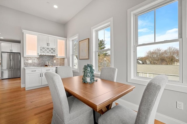 dining room with baseboards, a dry bar, recessed lighting, and light wood-style floors