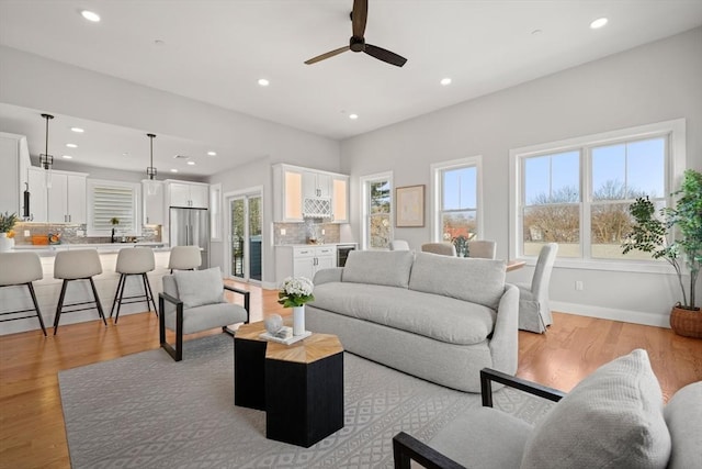 living area featuring wine cooler, recessed lighting, light wood-style floors, a ceiling fan, and baseboards