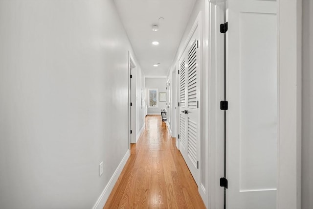 hall with light wood-type flooring, baseboards, and recessed lighting