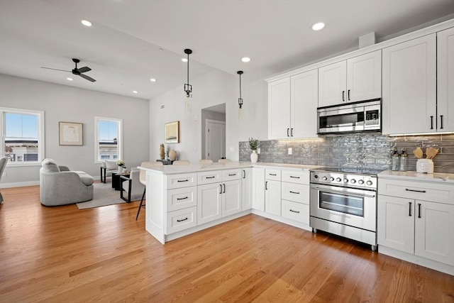 kitchen featuring a peninsula, light wood-style flooring, stainless steel appliances, and open floor plan