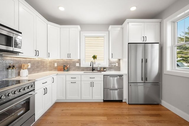 kitchen featuring a sink, light wood-style flooring, light countertops, and premium appliances