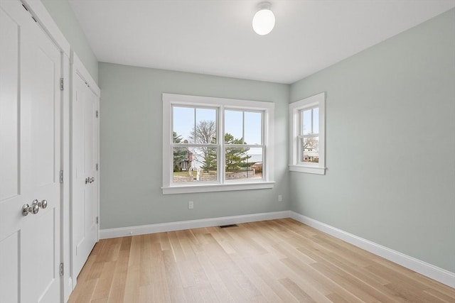 unfurnished bedroom with light wood-style flooring, visible vents, and baseboards