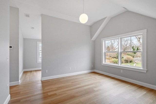 spare room with a wealth of natural light, visible vents, light wood-style flooring, and lofted ceiling