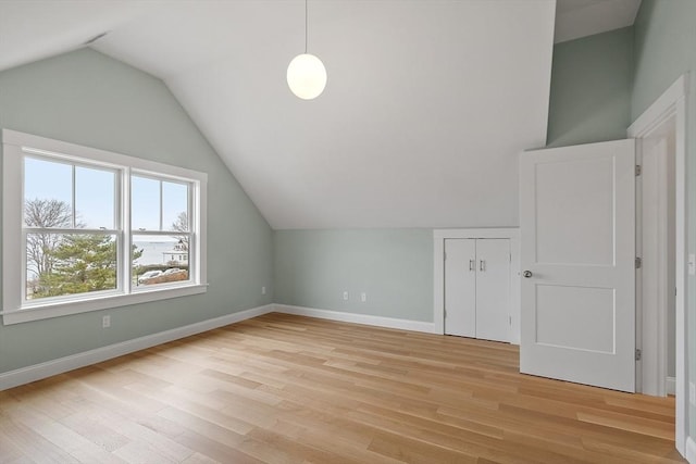 bonus room with baseboards, lofted ceiling, and light wood finished floors