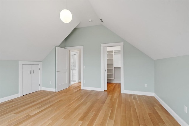 additional living space featuring baseboards, lofted ceiling, and light wood-style flooring