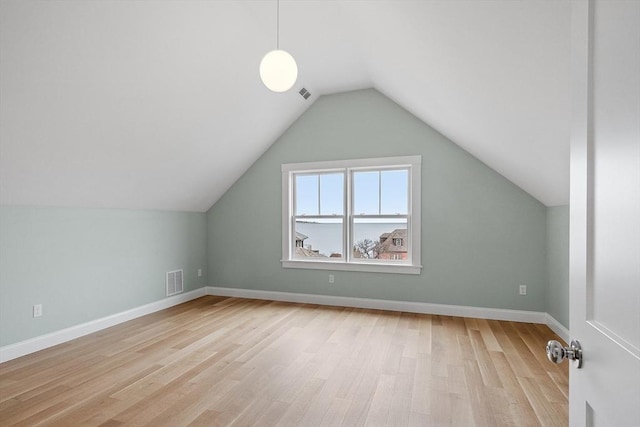 bonus room with visible vents, baseboards, light wood-style floors, and vaulted ceiling