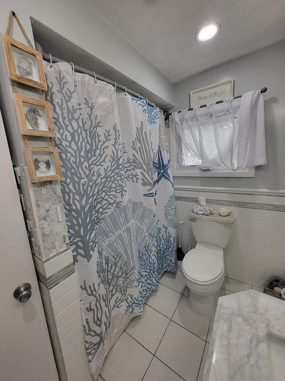 39 Cheever Rd, Malden, MA 02148 - bathroom with tile patterned flooring, curtained shower, a wainscoted wall, and tile walls