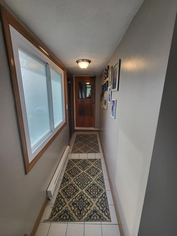 39 Cheever Rd, Malden, MA 02148 - doorway to outside with a baseboard radiator, light tile patterned flooring, and a textured ceiling