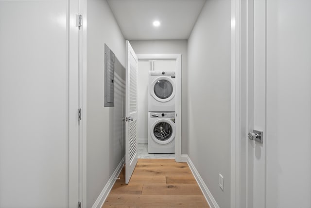 laundry room with stacked washer and clothes dryer and light wood-type flooring