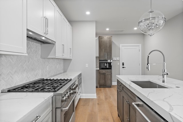 kitchen featuring white cabinetry, backsplash, stainless steel appliances, sink, and light hardwood / wood-style floors