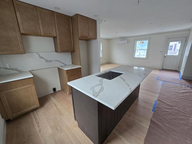 9 Swan St Unit 1, Beverly, MA 01915 - kitchen with light wood-style floors, light stone counters, a kitchen island, and a wall unit AC