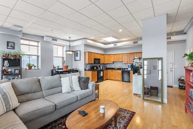 living room with a drop ceiling, light wood finished floors, and baseboards
