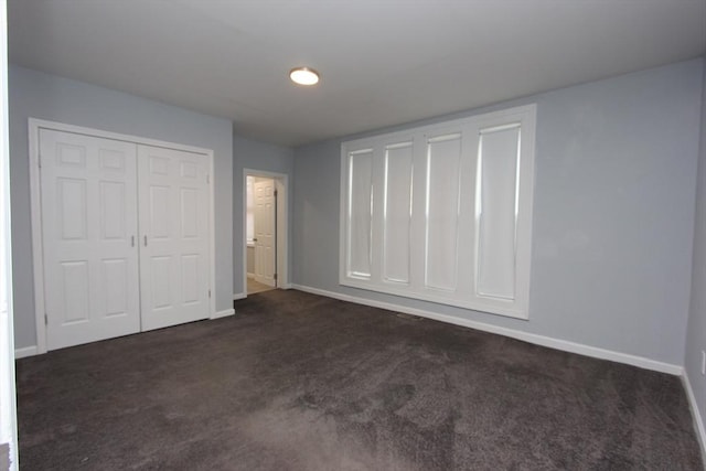 unfurnished bedroom with dark colored carpet and a closet