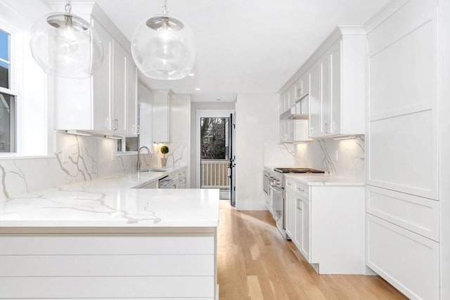 kitchen featuring hanging light fixtures, white cabinetry, a sink, light stone countertops, and high end range