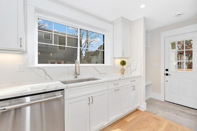 kitchen with decorative backsplash, dishwasher, light stone counters, white cabinetry, and a sink