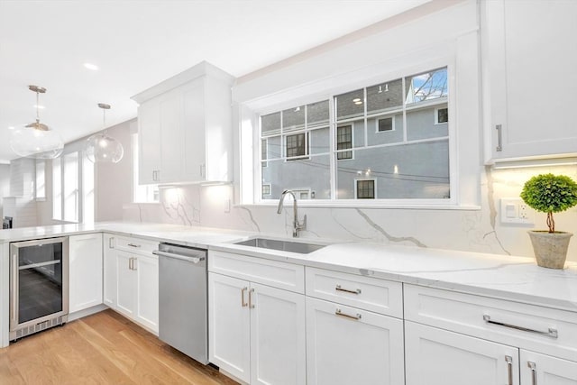 kitchen with wine cooler, hanging light fixtures, stainless steel dishwasher, white cabinets, and a sink