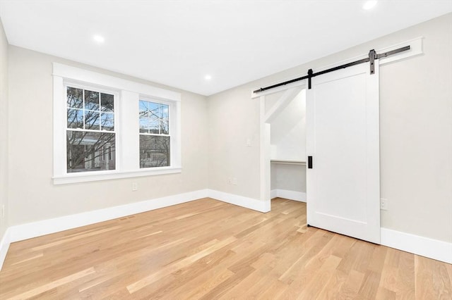 interior space featuring light wood-style floors, baseboards, and a barn door