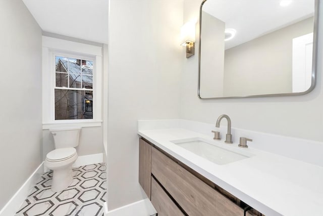 half bathroom featuring toilet, vanity, and baseboards