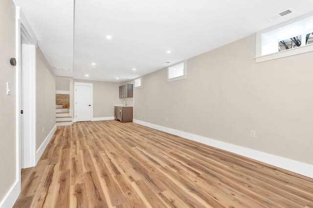 basement featuring stairs, a wealth of natural light, light wood-style flooring, and visible vents