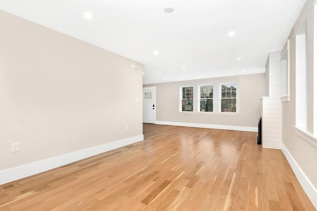 empty room with a healthy amount of sunlight, light wood-style flooring, and baseboards