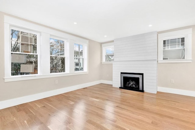 unfurnished living room with recessed lighting, a fireplace, light wood-style flooring, and baseboards