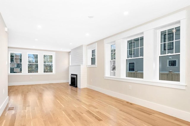 unfurnished living room featuring baseboards, visible vents, light wood-style floors, a fireplace, and recessed lighting