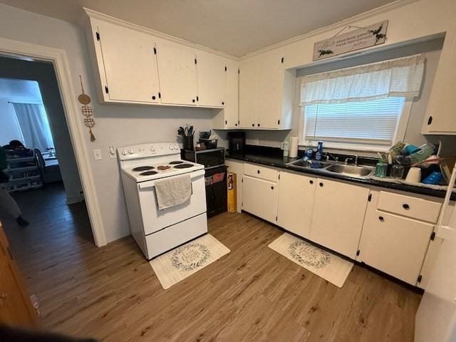 kitchen featuring a sink, white cabinetry, white range with electric cooktop, and wood finished floors