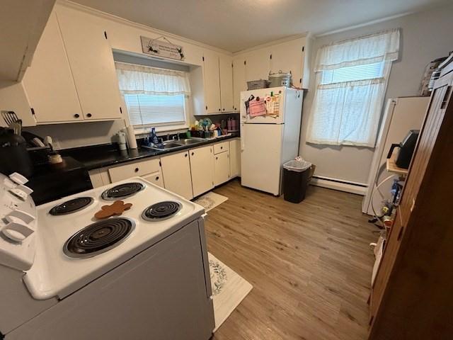 kitchen with light wood-style flooring, a baseboard heating unit, white appliances, a sink, and white cabinets